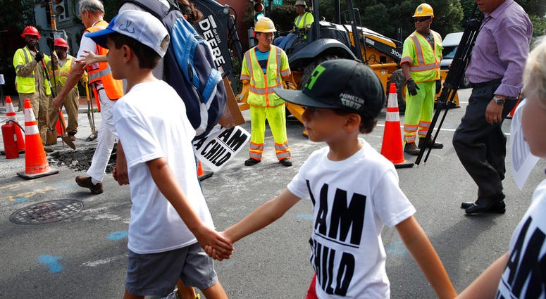 Construction workers watch as children hold hands during a march in protest of the separation of immigrant families, Thursday, July 26, 2018, on Capitol Hill in Washington. Construction workers watch as children hold hands during a march in protest of the separation of immigrant families, Thursday, July 26, 2018, on Capitol Hill in Washington.