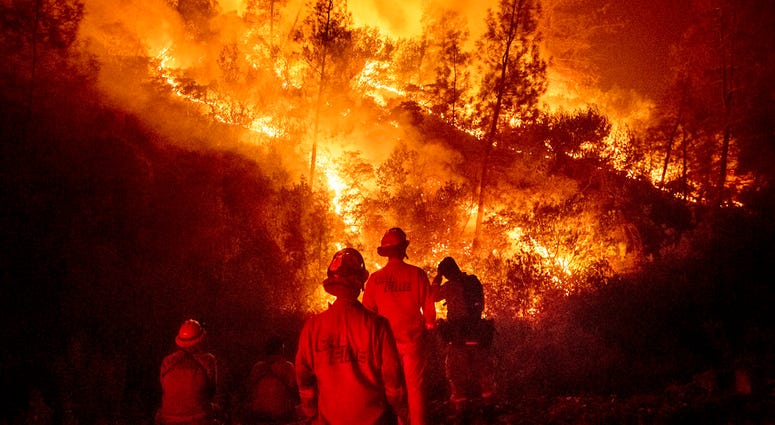 In this Aug. 7, 2018 file photo, firefighters monitor a backfire while battling the Ranch Fire, part of the Mendocino Complex Fire near Ladoga, Calif. In this Aug. 7, 2018 file photo, firefighters monitor a backfire while battling the Ranch Fire, part of the Mendocino Complex Fire near Ladoga, Calif.