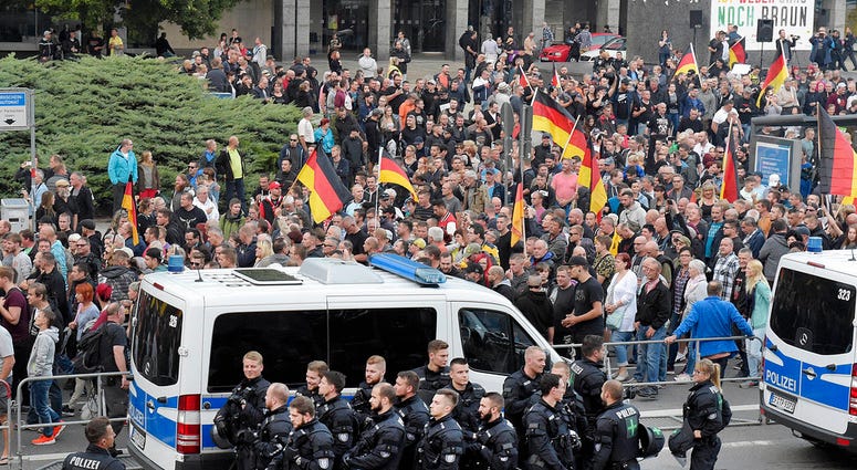 People are watched by police as they attend a demonstration in eastern Germany, Sept. 7, 2018, after several nationalist groups called for marches protesting the killing of a German man two weeks ago, allegedly by migrants from Syria and Iraq. People are watched by police as they attend a demonstration in eastern Germany, Sept. 7, 2018, after several nationalist groups called for marches protesting the killing of a German man two weeks ago, allegedly by migrants from Syria and Iraq.