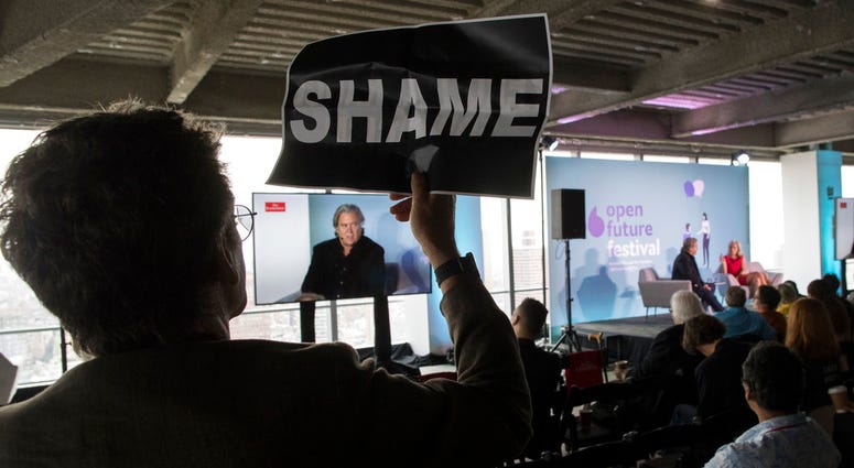 Stuart Waldman with Rise and Resist holds up a sign in silent protest as President Donald Trump's former chief strategist Steve Bannon speaks during an ideas festival sponsored by The Economist, Saturday, Sept. 15, 2018, in New York. Stuart Waldman with Rise and Resist holds up a sign in silent protest as President Donald Trump's former chief strategist Steve Bannon speaks during an ideas festival sponsored by The Economist, Saturday, Sept. 15, 2018, in New York.