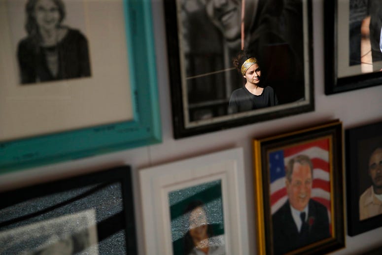 In this Sept. 25, 2018, photo, a woman looks at painted portraits of victims of the Oct. 1, 2017, mass shooting in Las Vegas on display at the Clark County Government Center in Las Vegas. In this Sept. 25, 2018, photo, a woman looks at painted portraits of victims of the Oct. 1, 2017, mass shooting in Las Vegas on display at the Clark County Government Center in Las Vegas.