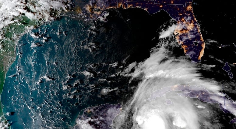 his satellite image provided by the National Oceanic and Atmospheric Administration shows a view of Tropical Storm Michael, lower right, churning as it heads toward the Florida Panhandle, Sunday, Oct. 7, 2018, at 6:52 p.m. Eastern Time. Tropical Storm Michael