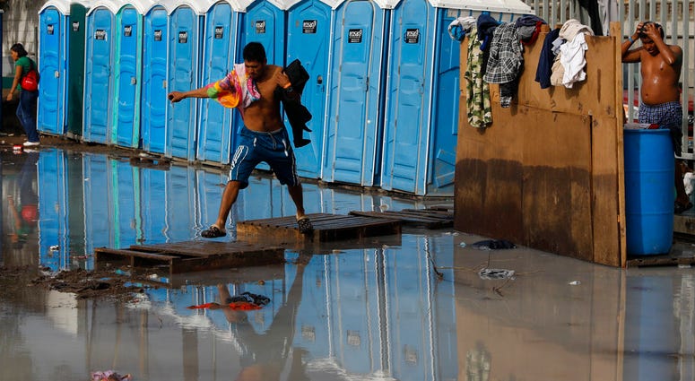 A migrant, part of the migrant caravan, try to cross a flooded area after bathing at a sports complex where more than 5,000 Central American migrants are sheltering in Tijuana, Mexico, Wednesday, Nov. 28, 2018. A migrant, part of the migrant caravan, try to cross a flooded area after bathing at a sports complex where more than 5,000 Central American migrants are sheltering in Tijuana, Mexico, Wednesday, Nov. 28, 2018.