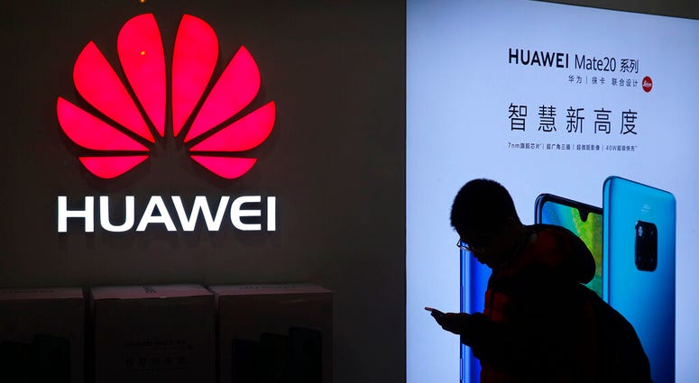In this Dec. 11, 2018, photo, a man browses his smartphone outside a Huawei store at a shopping mall in Beijing. In this Dec. 11, 2018, photo, a man browses his smartphone outside a Huawei store at a shopping mall in Beijing.
