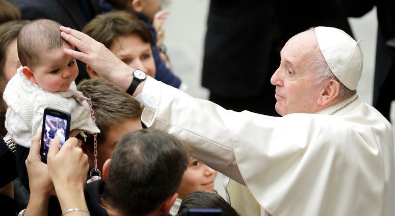 Pope Francis caresses a baby during an audience with Vatican employees, in the Pope Paul VI hall, at the Vatican, Friday, Dec. 21, 2018. Pope Francis