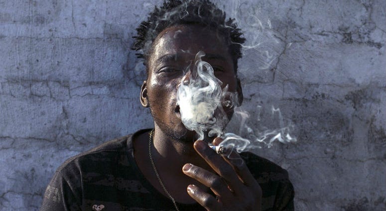 FILE - In this Tuesday, Sept. 18, 2018, file photo, a Malawian migrant Jonas smokes marijuana on the rooftop of an abandoned building in downtown Johannesburg. FILE - In this Tuesday, Sept. 18, 2018, file photo, a Malawian migrant Jonas smokes marijuana on the rooftop of an abandoned building in downtown Johannesburg.