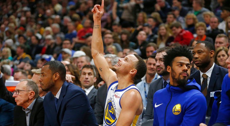 In this Dec. 19, 2018 file photo Golden State Warriors guard Stephen Curry (30) points skyward as he sits on the bench in the first half during an NBA basketball game against the Utah Jazz in Salt Lake City. Stephen Curry