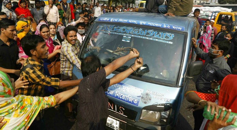 FILE - In this Wednesday, Jan. 9, 2019 file photo, Bangladeshi garment workers vandalize a vehicle during a protest in Savar, on the outskirts of Dhaka, Bangladesh. FILE - In this Wednesday, Jan. 9, 2019 file photo, Bangladeshi garment workers vandalize a vehicle during a protest in Savar, on the outskirts of Dhaka, Bangladesh.