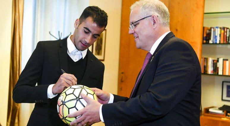 Refugee Hakeem al-Araibi, left, signs a ball for Australian Prime Minister Scott Morrison at Parliament House in Canberra, Australia, Thursday, Feb. 14, 2019. Refugee Hakeem al-Araibi, left, signs a ball for Australian Prime Minister Scott Morrison at Parliament House in Canberra, Australia, Thursday, Feb. 14, 2019.
