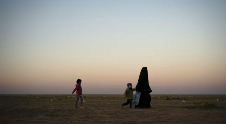 A woman walks with her children at a U.S.-backed Syrian Democratic Forces (SDF) screening area after being evacuated out of the last territory held by Islamic State militants, in the desert outside Baghouz, Syria, Friday, March 1, 2019 A woman walks with her children at a U.S.-backed Syrian Democratic Forces (SDF) screening area after being evacuated out of the last territory held by Islamic State militants, in the desert outside Baghouz, Syria, Friday, March 1, 2019