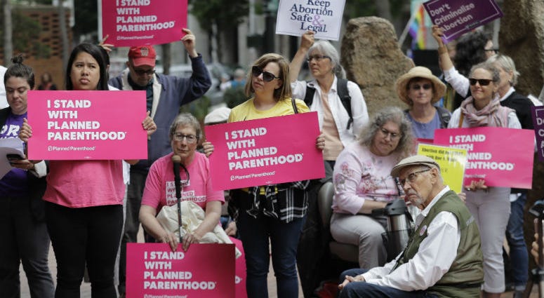 FILE - In this July 10, 2018 file photo, protesters hold signs supporting Planned Parenthood in Seattle, as they demonstrate against President Donald Trump and his choice of federal appeals Judge Brett Kavanaugh as his second nominee to the Supreme Court. FILE - In this July 10, 2018 file photo, protesters hold signs supporting Planned Parenthood in Seattle, as they demonstrate against President Donald Trump and his choice of federal appeals Judge Brett Kavanaugh as his second nominee to the Supreme Court.