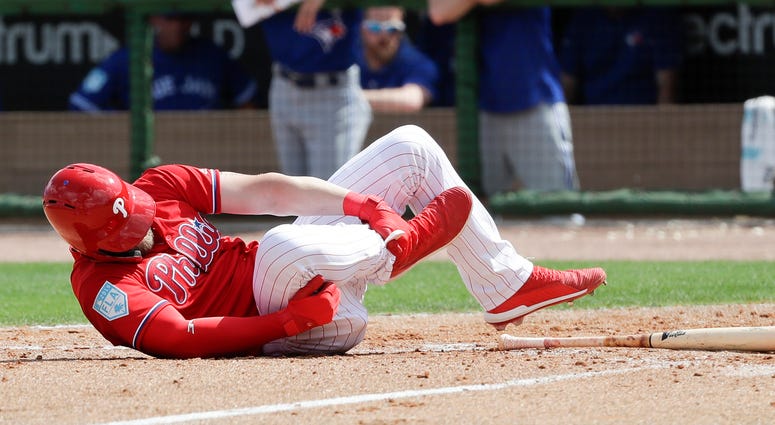 Philadelphia Phillies' Bryce Harper rolls on the dirt holding his leg after getting hit by a pitch against the Toronto Blue Jays during the sixth inning in a spring training baseball game, Friday, March 15, 2019, in Clearwater, Fla. Philadelphia Phillies' Bryce Harper rolls on the dirt holding his leg after getting hit by a pitch against the Toronto Blue Jays during the sixth inning in a spring training baseball game, Friday, March 15, 2019, in Clearwater, Fla.