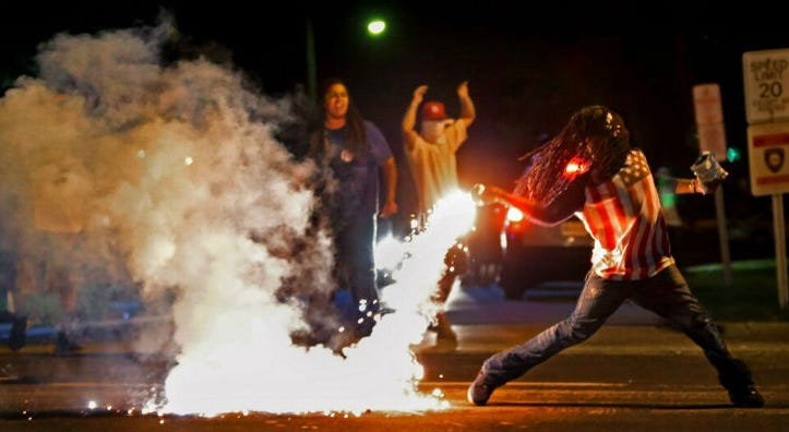 FILE - In this Aug. 13, 2014, file photo Edward Crawford Jr., returns a tear gas canister fired by police who were trying to disperse protesters in Ferguson, Mo. Edward Crawford Jr., returns a tear gas canister fired by police who were trying to disperse protesters in Ferguson, Mo.