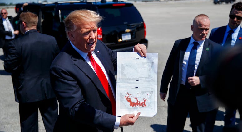 President Donald Trump holds a a copy of two maps of Syria as he arrives on Air Force One, Friday, March 22, 2019, at Palm Beach International Airport, in West Palm Beach, Fla. President Donald Trump
