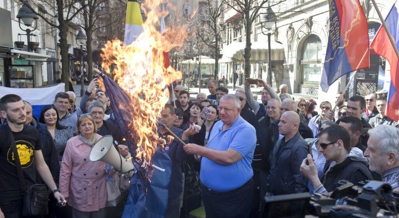 Vojislav Seselj, center, the leader of the ultranationalist Serbian Radical Party, holds a burning NATO flag as he and others gather for a protest in Belgrade, Serbia, Sunday, March 24, 2019. Members of the ultranationalist Serbian Radical Party gathered for a protest on Sunday in the Serbian capital to mark the 20th anniversary of the NATO led bombing campaign against Serbia in 1999.