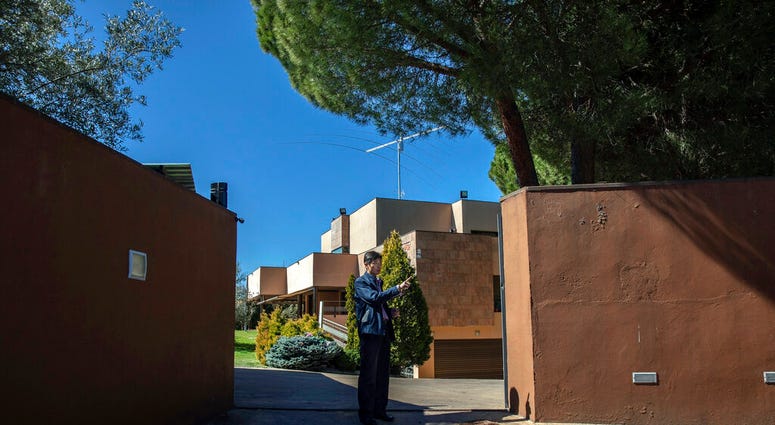 In this Wednesday, March 13, 2019 photo, a member of the North Korea's embassy tells reporters not to take pictures of the diplomatic building in Madrid, Spain. A Spanish court is accusing an American, Mexican and South Korean part of a 10-strong group that led an attack on the North Korean Embassy in February, saying the FBI was offered stolen data.