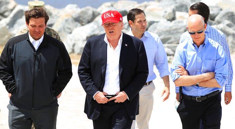 President Donald Trump walks with, from left, Florida Gov. Ron DeSantis, Sen. Marco Rubio, R-Fla., and Sen. Rick Scott, R-Fla., during a visit to Lake Okeechobee and Herbert Hoover Dike at Canal Point, Fla., Friday, March 29, 2019. President Donald Trump