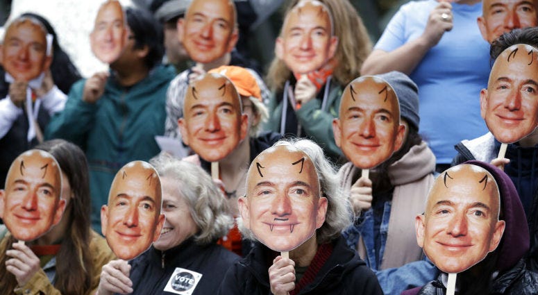 FILE - In this Oct. 31, 2018, file photo, demonstrators hold images of Amazon CEO Jeff Bezos near their faces during a Halloween-themed protest at Amazon headquarters over the company's facial recognition system, "Rekognition," in Seattle. FILE - In this Oct. 31, 2018, file photo, demonstrators hold images of Amazon CEO Jeff Bezos near their faces during a Halloween-themed protest at Amazon headquarters over the company's facial recognition system, "Rekognition," in Seattle.
