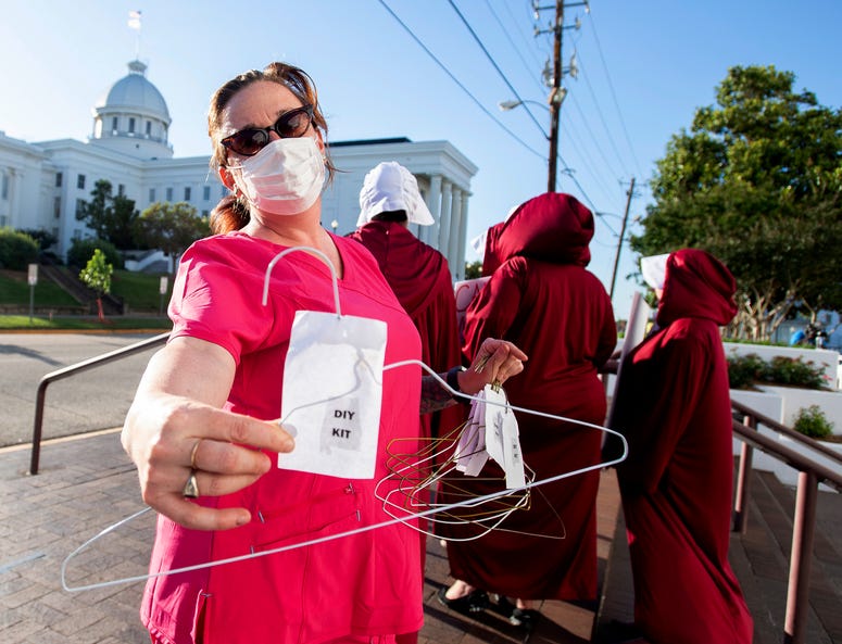 Laura Stiller hands out coat hangers as she talks about illegal abortions during a rally against a ban on nearly all abortions outside of the Alabama State House in Montgomery, Ala., on Tuesday, May 14, 2019. Abortion advocates protest