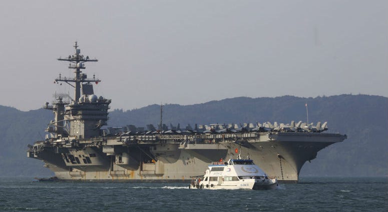 FILE - In this March 5, 2018, file photo, a Vietnamese passenger boat sails past U.S. aircraft carrier USS Carl Vinson as it docks in Danang bay, Vietnam. A U.S. sailor has pleaded guilty to espionage and sentenced to three years after admitting he took classified information about a Navy's nuclear-powered warship and planned to give it to a journalist and then defect to Russia officials said Friday, May 24