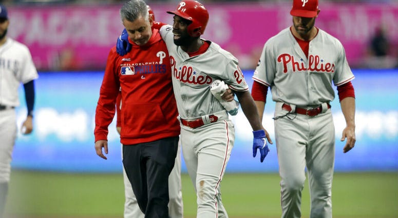Philadelphia Phillies' Andrew McCutchen, center, is helped by a trainer after being injured while trying to get back to first base during the first inning of a baseball game against the San Diego Padres Monday, June 3, 2019, in San Diego. Philadelphia Phillies' Andrew McCutchen, center, is helped by a trainer after being injured while trying to get back to first base during the first inning of a baseball game against the San Diego Padres Monday, June 3, 2019, in San Diego.