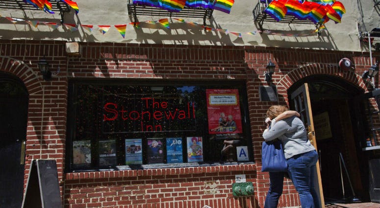 FILE- In this June 12, 2016 file photo, a couple embraces outside the Stonewall Inn in New York. On Thursday, June 6, 2019, Commissioner James O'Neill apologized for the 1969 police raid at the Stonewall Inn, which catalyzed the modern LGBT rights movement.