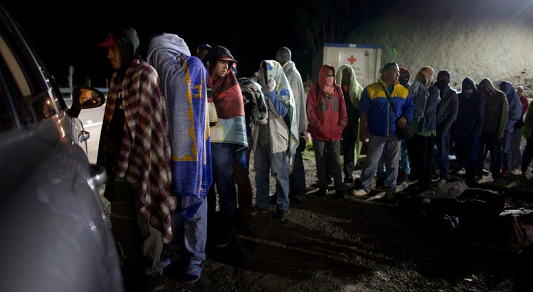 In this Aug. 31, 2018 file photo, Venezuelan migrants line up for free bread and coffee, donated by a Colombian family from their car, at a gas station in Pamplona, Colombia. Venezuelan migrants