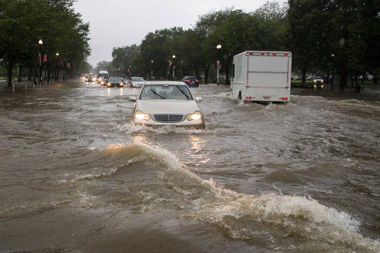 Heavy rainfall flooded the intersection of 15th Street and Constitution Ave., NW, stalling cars in the street, Monday, July 8, 2019, in Washington. Flooding