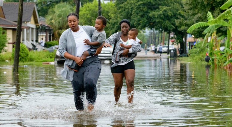 Jalana Furlough carries her son Drew Furlough as Terrian Jones carries Chance Furlough on Belfast Street near Eagle Street in New Orleans after flooding from a tropical wave system in the Gulf Mexico that dumped lots of rain in Wednesday, July 10, 2019. Jalana Furlough carries her son Drew Furlough as Terrian Jones carries Chance Furlough on Belfast Street near Eagle Street in New Orleans after flooding from a tropical wave system in the Gulf Mexico that dumped lots of rain in Wednesday, July 10, 2019.