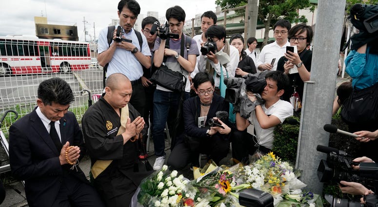 Japanese Diet member, Kenta Izumi, left, and Buddhist monk, Matsumoto Genkun, pay respects at a makeshift memorial site in front of burned Kyoto Animation Studio building, background left, Friday, July 19, 2019, in Kyoto, Japan. Japanese Diet member, Kenta Izumi, left, and Buddhist monk, Matsumoto Genkun, pay respects at a makeshift memorial site in front of burned Kyoto Animation Studio building, background left, Friday, July 19, 2019, in Kyoto, Japan.