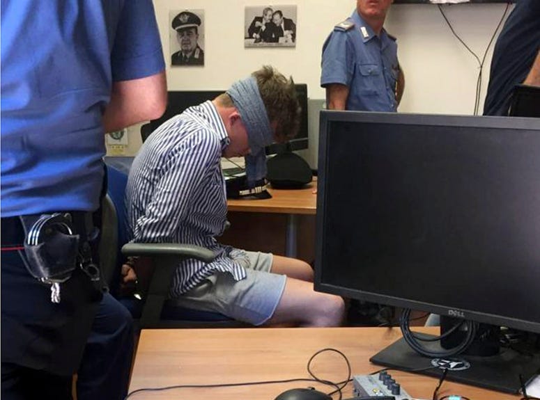 In this photo obtained from Italian Carabinieri, Gabriel Christian Natale-Hjorth sits blindfolded in a police station in Rome on Friday July 26, 2019. Gabriel Christian Natale-Hjorth