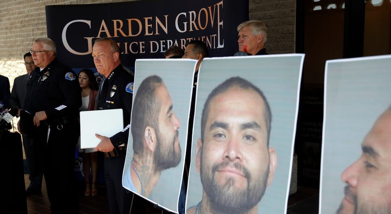 Garden Grove Police Chief Tom DaRe, center, and PIO Carl Whitney address the media next to a booking mug shot of Zachary Castaneda posted outside of the Garden Grove Police Department headquarters in Garden Grove, Calif., Thursday, Aug. 8, 2019. Zachary Castaneda