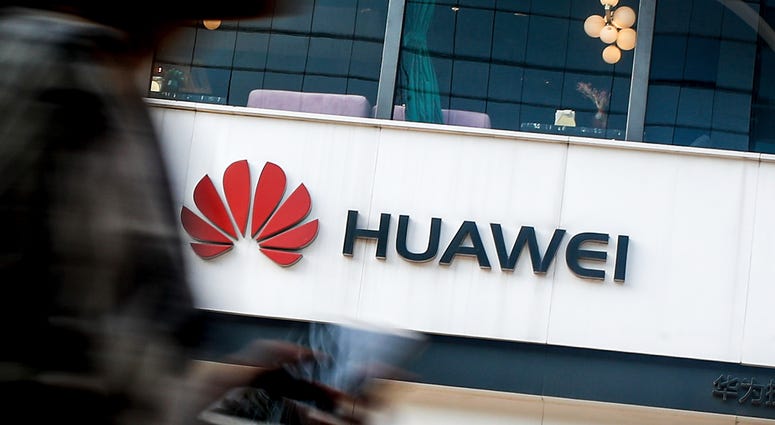 In this July 30, 2019, file photo a woman walks by a Huawei retail store in Beijing. Huawei