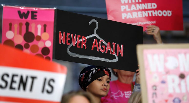 August Mulvihill, of Norwalk, Iowa, center, holds a sign during a rally to protest recent abortion bans at the Statehouse in Des Moines, Iowa. August Mulvihill, of Norwalk, Iowa, center, holds a sign during a rally to protest recent abortion bans at the Statehouse in Des Moines, Iowa on May 21, 2019.
