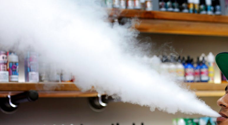 FILE - In this Tuesday, Sept. 3, 2019 file photo, a salesman at a vape shop exhales while using an e-cigarette in Maine. A salesman at a vape shop exhales while using an e-cigarette in Maine.