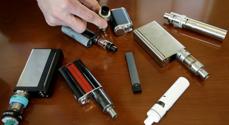 In this Tuesday, April 10, 2018 photo, a high school principal displays vaping devices that were confiscated from students at the school in Massachusetts. Vapes