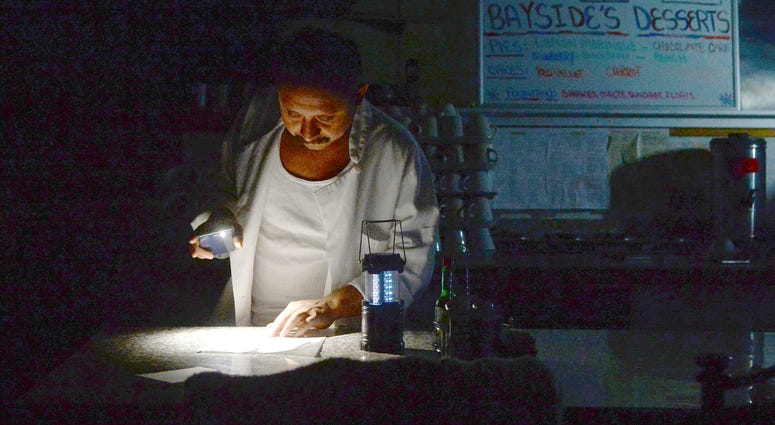 Carlos Lama of Bayside Cafe, which was among businesses to lose power due to PG&E's public safety power shutoff, uses an LED lamp and light from his phone at the counter of the restaurant in Sausalito, Calif. Carlos Lama of Bayside Cafe, which was among businesses to lose power due to PG&E's public safety power shutoff, uses an LED lamp and light from his phone at the counter of the restaurant in Sausalito, Calif.
