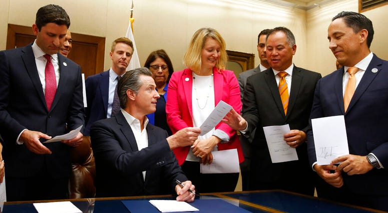 California Gov. Gavin Newsom, seated hands Assemblyman Phil Ting, D-San Francisco, second from right, a copy of his bill that Newsom signed at the Capitol in Sacramento, Calif., Friday, Oct. 11, 2019. California Gov. Gavin Newsom, seated hands Assemblyman Phil Ting, D-San Francisco, second from right, a copy of his bill that Newsom signed at the Capitol in Sacramento, Calif., Friday, Oct. 11, 2019.