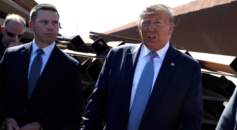 In this Sept. 18, 2019, file photo, President Donald Trump talks with reporters as he tours a section of the southern border wall, in Otay Mesa, Calif., as acting Homeland Secretary Kevin McAleenan listens. President Donald Trump and acting Homeland Secretary Kevin McAleenan