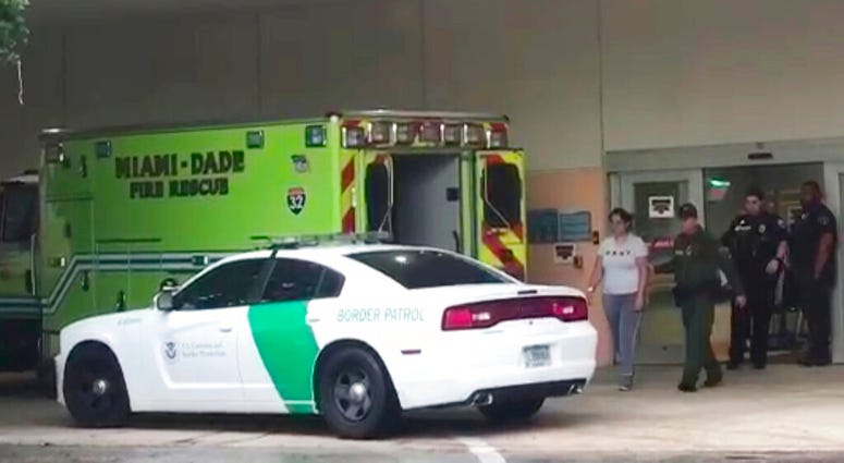 A border patrol agents escorts a woman to a patrol car Sunday, Oct. 13, 2019, at Aventura Hospital in Aventura, Fla. The woman had been detained by border patrol agents, when she fell ill. A border patrol agents escorts a woman to a patrol car Sunday, Oct. 13, 2019, at Aventura Hospital in Aventura, Fla. The woman had been detained by border patrol agents, when she fell ill.
