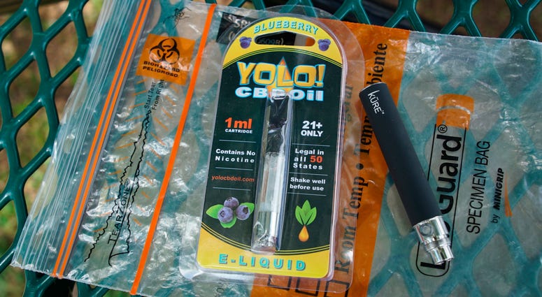 In this May 8, 2019, file photo, a Yolo! brand CBD oil vape cartridge sits alongside a vape pen on a biohazard bag on a table at a park in Ninety Six, S.C. In this May 8, 2019, file photo, a Yolo! brand CBD oil vape cartridge sits alongside a vape pen on a biohazard bag on a table at a park in Ninety Six, S.C.