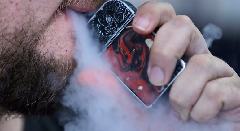 In this Friday, Oct. 4, 2019 photo, a man using an electronic cigarette exhales in Mayfield Heights, Ohio. Vaping-related illnesses in the U.S. are still rising, though at a slightly slower pace.