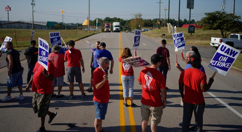 In this Sept. 16, 2019, file photo striking plant workers block the passage of two trucks outside the General Motor assembly plant in Bowling Green, Ky.