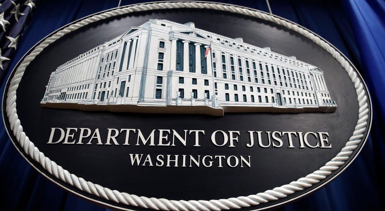 In this Thursday, April 18, 2019, file photo, a sign for the Department of Justice hangs in the press briefing room at the Justice Department, in Washington. In this Thursday, April 18, 2019, file photo, a sign for the Department of Justice hangs in the press briefing room at the Justice Department, in Washington.