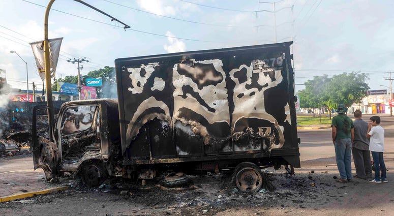 A burnt out truck used by gunmen smolders on an intersection, a day after street battles between gunmen and security forces in Culiacan, Mexico, Friday Oct. 18, 2019. A burnt out truck used by gunmen smolders on an intersection, a day after street battles between gunmen and security forces in Culiacan, Mexico, Friday Oct. 18, 2019.