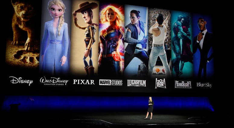 Characters from Disney and Fox movies are displayed behind Cathleen Taff, president of distribution, franchise management, business and audience insight for Walt Disney Studios during a presentation at CinemaCon 2019. Disney+