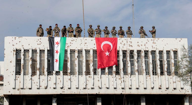 Turkish soldiers, right, and Turkey-backed opposition fighters stand atop a building next to their flags in Syrian town of Ras al Ayn, northeastern Syria, Wednesday, Oct. 23, 2019. Turkish soldiers, right, and Turkey-backed opposition fighters stand atop a building next to their flags in Syrian town of Ras al Ayn, northeastern Syria, Wednesday, Oct. 23, 2019.