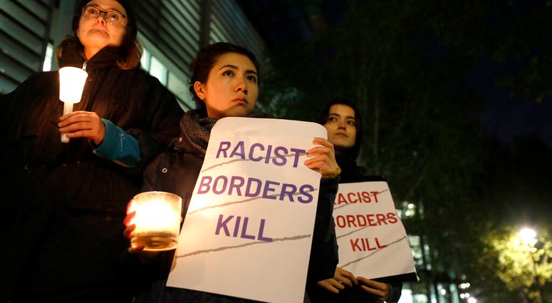 Demonstrators hold banners and candles during a vigil for the 39 lorry victims, outside the Home Office in London, Thursday, Oct. 24, 2019. Demonstrators hold banners and candles during a vigil for the 39 lorry victims, outside the Home Office in London.
