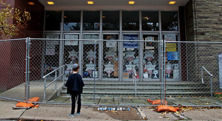 A young boy looks at the fenced off entrance to the Tree of Life synagogue in Pittsburgh on Sunday, Oct. 27, 2019, the first anniversary of the shooting at the synagogue, that killed 11 worshippers. Tree of Life synagogue