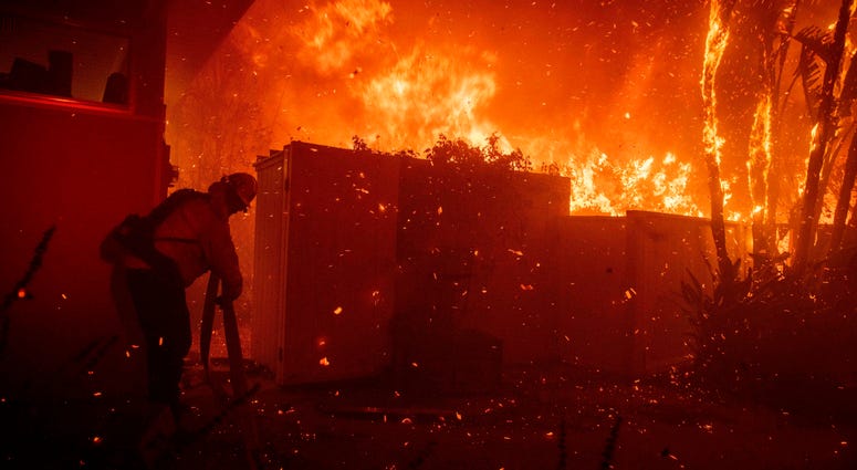 Firefighters try to save a home on Tigertail Road from the Getty fire, Monday, Oct. 28, 2019, in Los Angeles, Calif. Firefighters